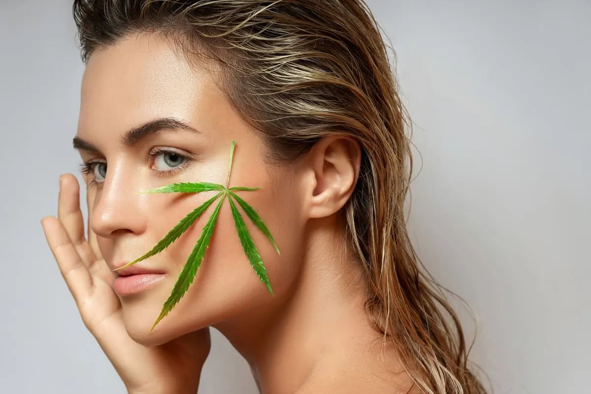 Une femme avec une feuille de cannabis CBD sur la peau, symbolisant les bienfaits du CBD pour la peau.
